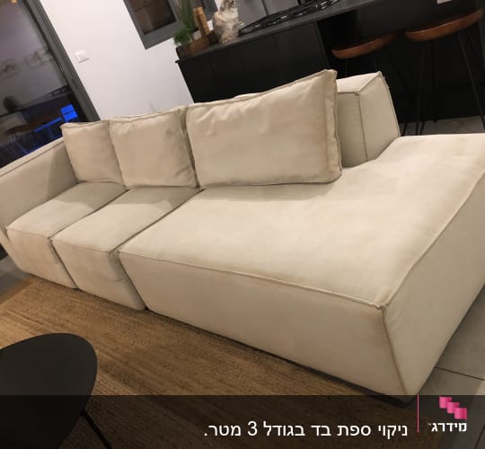ספה בהירה עם כריות על שטיח